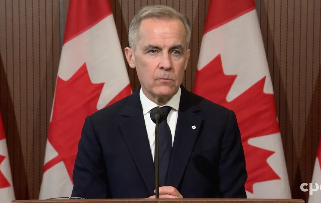 Close-up of Mark Carney speaking into a microphone at media announcement, mid-gesture and facing the audience