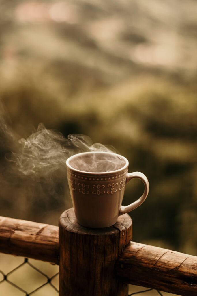 a steaming cup of coffee sits on a fence post
