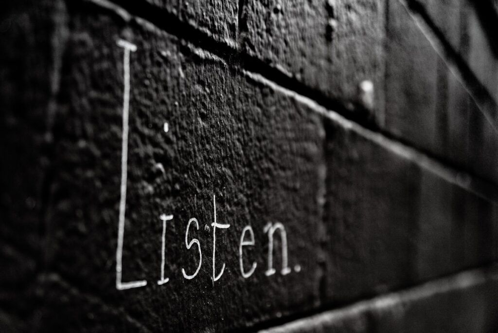 a black and white photo of the word listen written on a brick wall