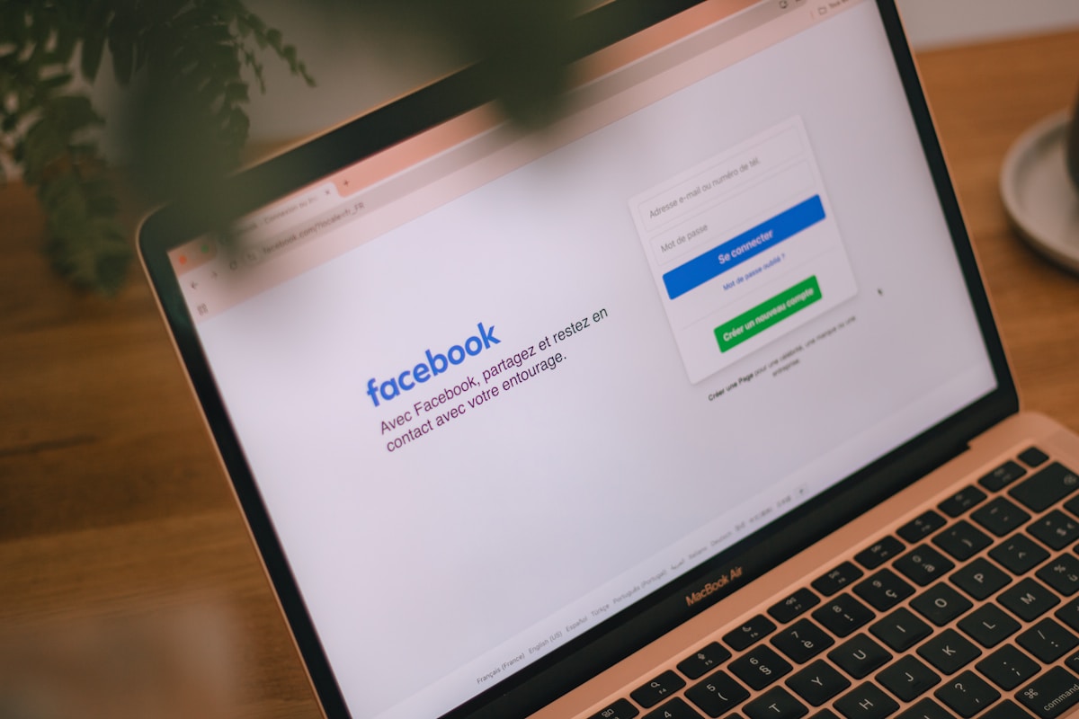 A laptop displays the facebook login page.