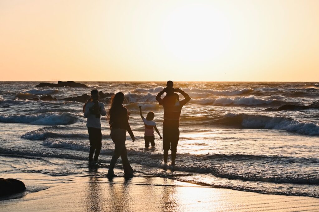 A group of people standing on top of a beach next to the ocean