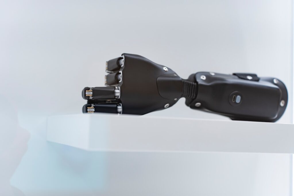 A black prosthetic hand rests on a white shelf.