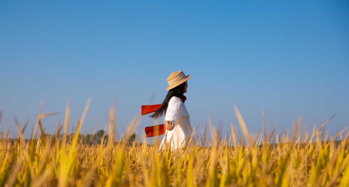 Woman in hat walking through golden field