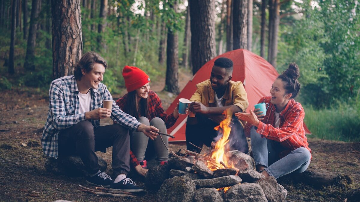 Friends gathered around a campfire in a forest.
