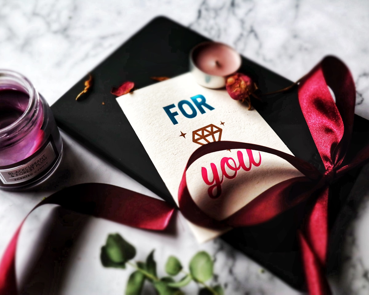 greeting card beside a red ribbon and tealight candle